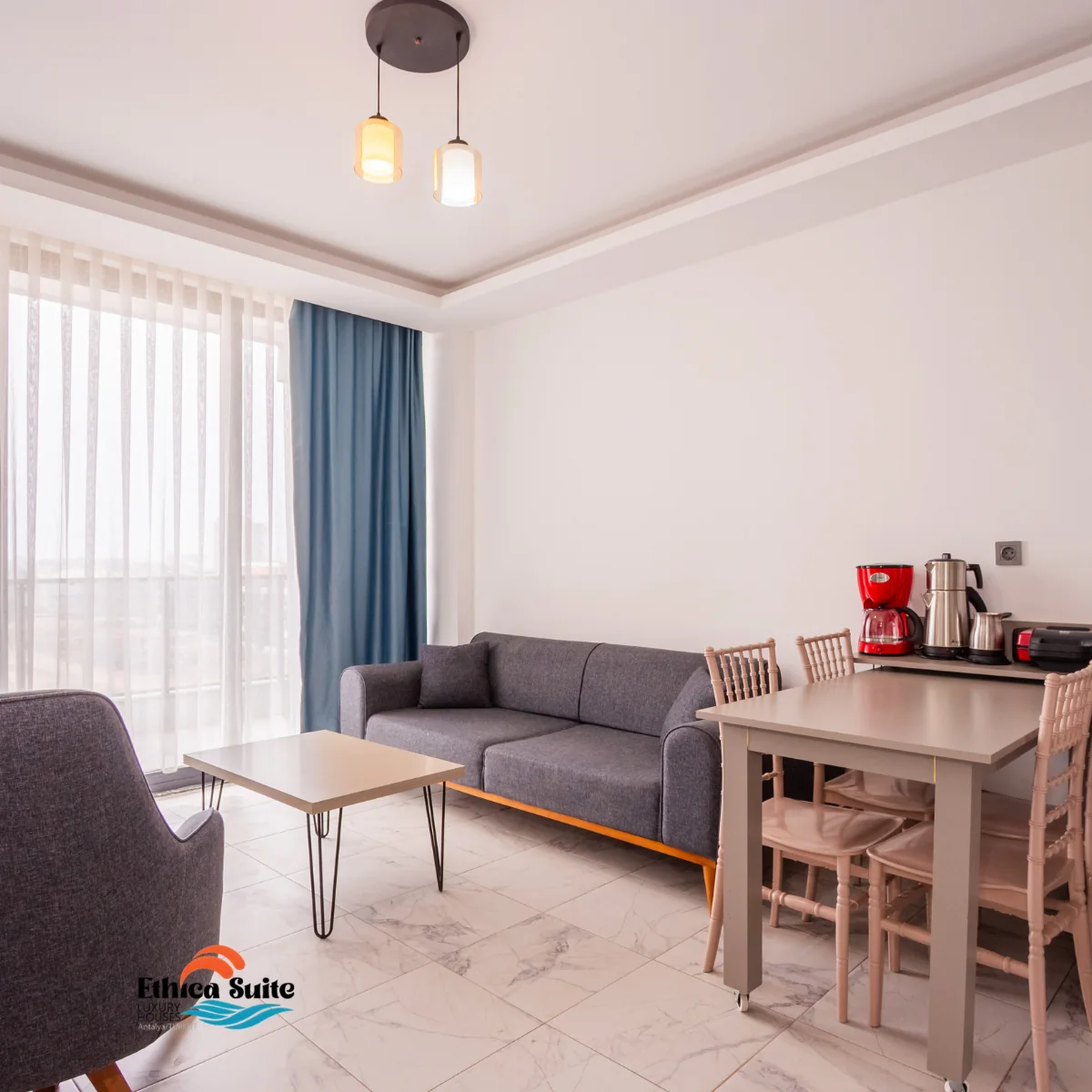 Süit dairenin salonunda oturma grubu, yemek masası ve kahve makinesi
